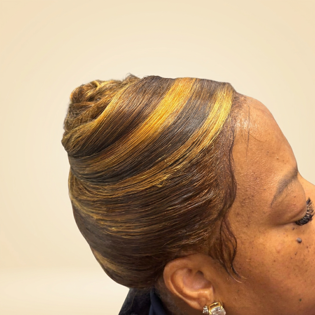 Polished updo with warm honey highlights and sleek sculpted styling